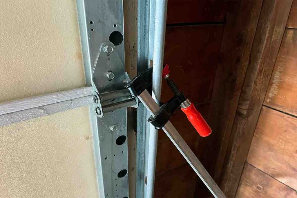 Person securing a garage door with clamps