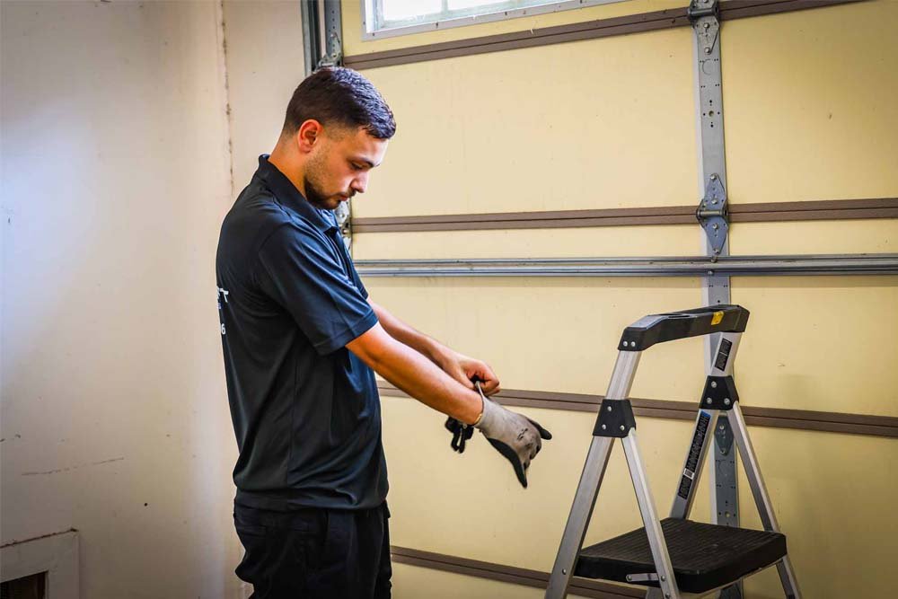 Technician tightening loose bolts on a garage door track.