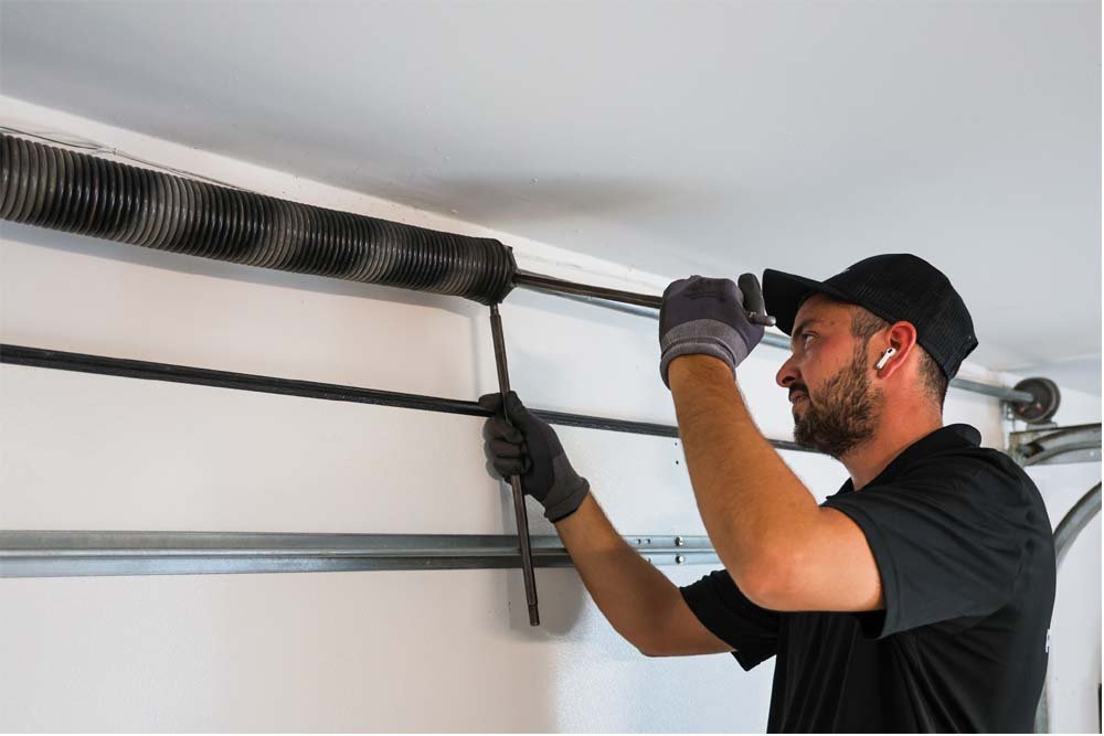 technician replacing garage door springs with tools
